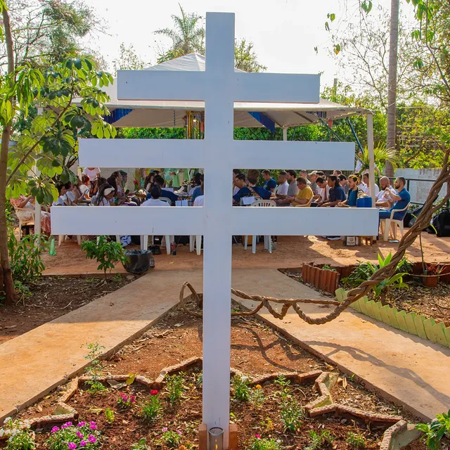 O Cruzeiro no jardim da Estrela Azul, com a comunidade reunida ao fundo sob a tenda