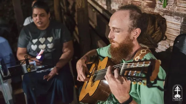 Homem tocando violão ao lado de uma mulher cantando, durante o feitio