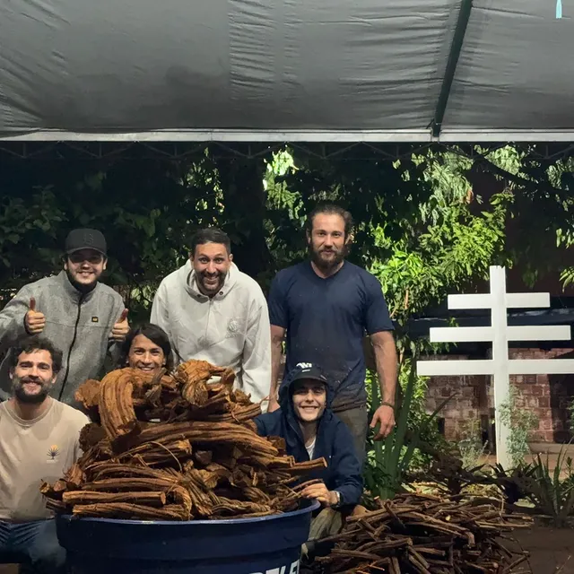 Equipe da Estrela Azul reunida com o cipó recém-colhido, sorrindo ao lado do Cruzeiro